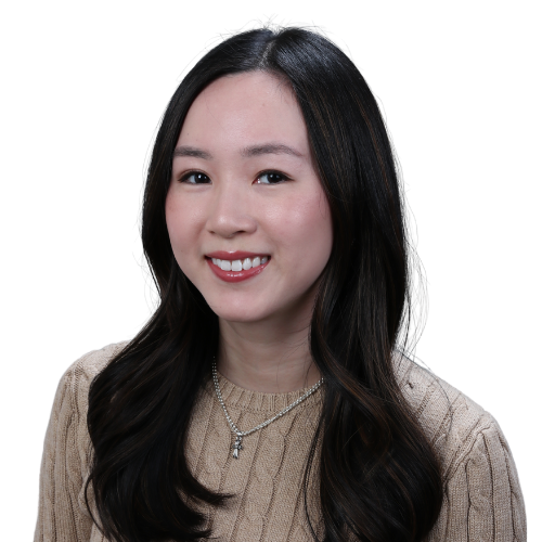 Portrait of a smiling young Asian woman with long dark hair, wearing a beige knit sweater and a silver necklace against a white background.